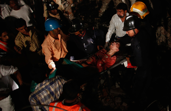 Rescue workers carry a woman who survived from a collapsed residential building in Thane, on the outskirts of Mumbai April 4, 2013 (Reuters / Danish Siddiqui)