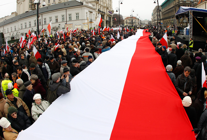 People hold a Polish flag during a remembrance ceremony for the 2010 plane crash that killed former Polish President Lech Kaczynski and 95 others outside of the Presidential Palace in Warsaw April 10, 2013 (Reuters / Peter Andrews)