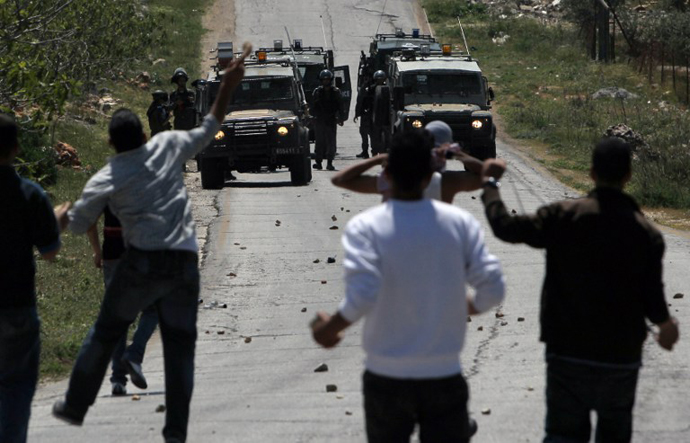 Palestinians throw stones towards Israeli security forces during clashes following a protest against the expropriation of Palestinian land by Israel in the West Bank village of Silwad, east of Ramallah, on April 12, 2013. (AFP Photo / Abbas Momani)