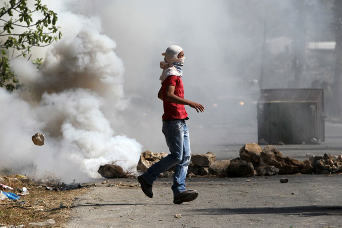 A Palestinian wearing a mask looks on during clashes with Israeli security forces following a protest against the expropriation of Palestinian land by Israel in the West Bank village of Silwad, east of Ramallah, on April 12, 2013. (AFP Photo / Abbas Momani)