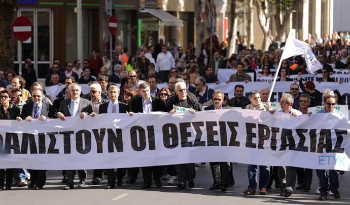Employees of the bank hold banners as they march towards the parliament on April 4, 2013 during a demonstration in the Cypriot capital, Nicosia, over fears that pensions may be at risk under Cyprus's bailout, as more details emerged of biting austerity measures imposed on the cash-strapped island (AFP Photo / Patrick Baz)