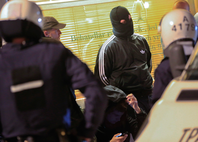 Police officers of the Swedish riot police search a masked man in the Malarhojden suburb of Stockholm, Sweden on early Saturday morning of May 25, 2013, the sixth straight night of unrest that flared in Stockholm's immigrant-dominated suburbs (AFP Photo)