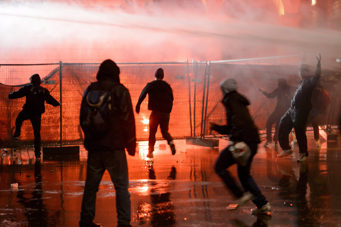 Members of the Black bloc are sprayed by a water cannon in front of the Swiss House of Parliament on late May 25, 2013 in the center of Switzerland's capital Bern during the 3rd edition of "Tanz Dich Frei" (Dance Yourself Free) a politically-tinged techno parade and mass unauthorised rally (AFP Photo / Fabrice Coffrini)