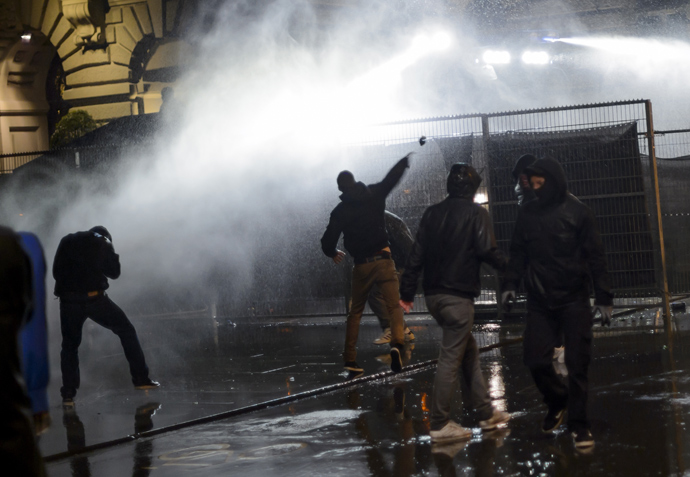 Members of the Black bloc are sprayed by a water cannon in front of the Swiss House of Parliament on late May 25, 2013 in the center of Switzerland's capital Bern during the 3rd edition of "Tanz Dich Frei" (Dance Yourself Free) a politically-tinged techno parade and mass unauthorised rally (AFP Photo / Fabrice Coffrini)