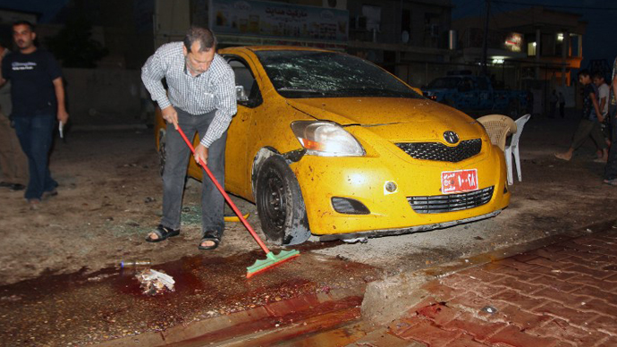 An Iraqi clears the blood from the pavement after a suicide bomb attack outside Al-Zahraa husseiniyah, a Shiite place of worship, in the northern Iraq city of Kirkuk on May 16, 2013. (AFP Photo / Ali Al-Saadi)