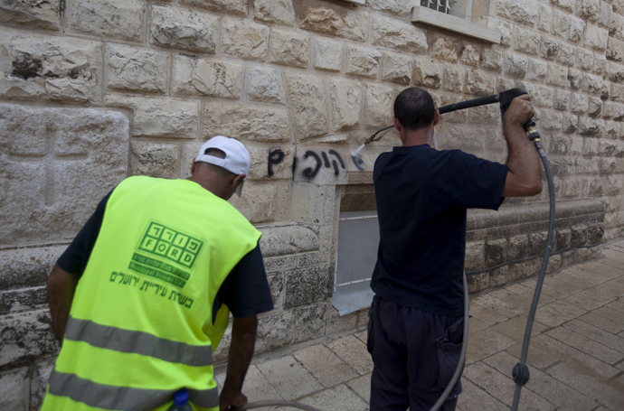 A Jerusalem municipality worker cleans anti-Christian graffiti reading in Hebrew, "Christians monkeys" that was daubed on the Church of the Dormition, one of Jerusalem's leading pilgrimage sites, on May 31, 2013 (AFP Photo / Ahmad Gharabli)