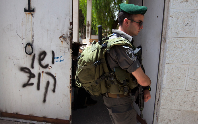 An Israeli border guard stands next to anti-Christian graffiti reading in Hebrew, "Jesus is monkey" that was daubed on the Church of the Dormition, one of Jerusalem's leading pilgrimage sites, early on May 31, 2013 (AFP Photo / Ahmad Gharabli)