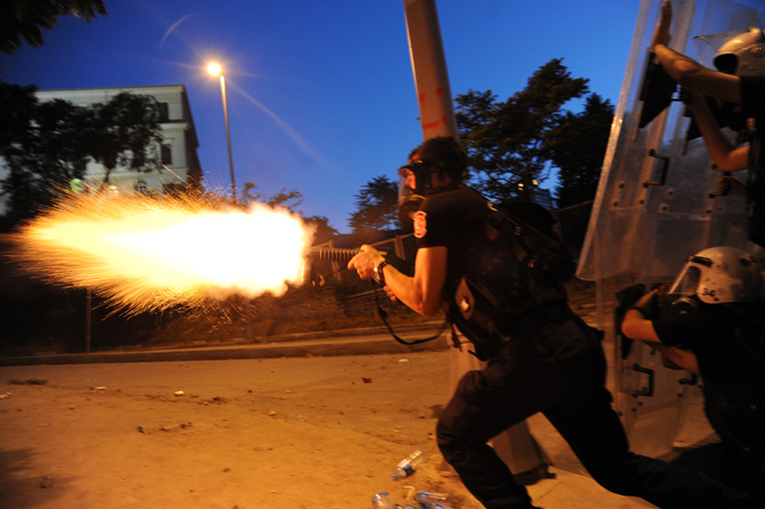Turkish riot police officer fires tear gas during clashes with protestors between Taksim and Besiktas in Istanbul on June 3, 2013 during a demonstration against the demolition of the park (AFP Photo / Bulent Kilic)