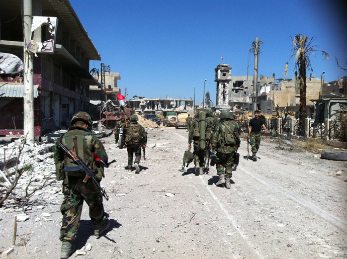 Syrian army's soldiers walk in a street left in ruins on June 5, 2013 in the city of Qusayr in Syria's central Homs province (AFP Photo / Str)