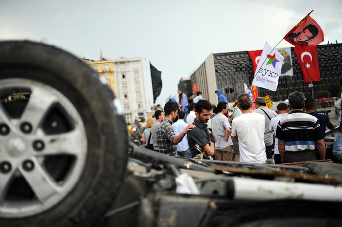 People look at Turkish riot policemen position at Taksim Gezi park in Istanbul on June 13, 2013 (AFP Photo / Bulent Kilic)