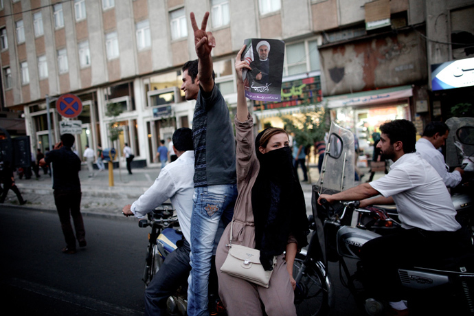 An Iranian woman holds a portrait of moderate presidential candidate Hassan Rouhani as she rides on a motorcycle along Valiasr street in Tehran on June 15, 2013 after he was elected as president (AFP Photo / Behrouz Mehri)