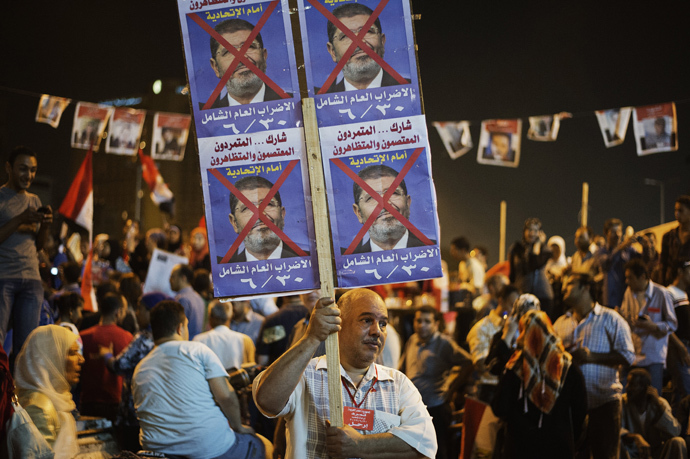 An Egyptian man holds a placard as hundreds of Egyptian anti-government protesters shout political slogans against Egyptian President Mohammed Morsi in Egypt's landmark Tahrir square as they watch Morsi's speech protesting against government and the Muslim Brotherhood on June 26, 2013 in Cairo, Egypt (AFP Photo / Gianluigi Guercia)
