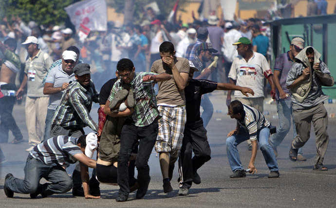 Supporters of ousted Egyptian president Mohamed Morsi evacuate a man who was shot during a gun battle outside the Cairo headquarters of the Republican Guard on July 5, 2013. (AFP Photo/Mahmud Hams)