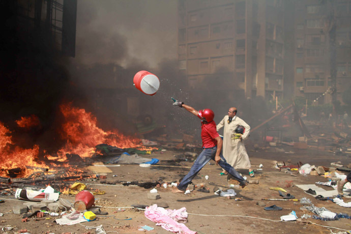 A supporter of the Muslim Brotherhood and Egypt's ousted president Mohamed Morsi throws a water container onto a fire during clashes with police in Cairo on August 14, 2013, as security forces backed by bulldozers moved in on two huge pro-Morsi protest camps, launching a long-threatened crackdown that left dozens dead. (AFP Photo/Mosaab El-Shamy)