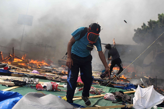 A supporter of the Muslim Brotherhood and Egypt's ousted president Mohamed Morsi searches through the debris while a fellow demonstrator throws an object during clashes with police in Cairo on August 14, 2013, as security forces backed by bulldozers moved in on two huge pro-Morsi protest camps, launching a long-threatened crackdown that left dozens dead. (AFP Photo/Mosaab El-Shamy)