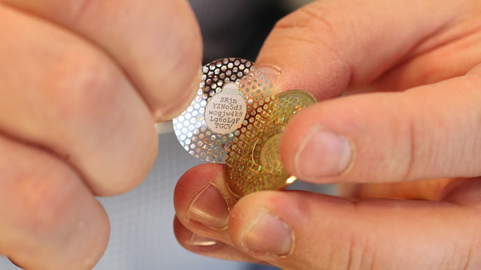 Software engineer Mike Caldwell peels back the hologram of a new Bitcoin he minted to reveal a code in his shop on April 26, 2013 in Sandy, Utah. (George Frey/Getty Images/AFP)