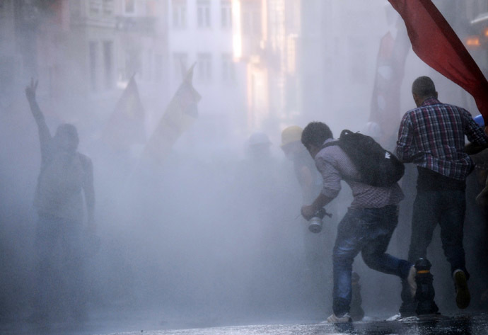 Protesters take cover from a water cannon during clashes with police on Istiklal Avenue in Istanbul on July 6, 2013. (AFP Photo/Bulent Kilic)
