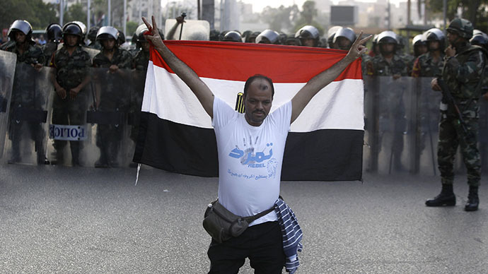 Member of the "Tamarod - Rebel!" petition drive against Mursi, gestures with an Egyptian flag in front of army soldiers standing guard in front of protesters who are against Egyptian President Mursi, near the Republican Guard headquarters in Cairo (Reuters / Amr Dalsh)