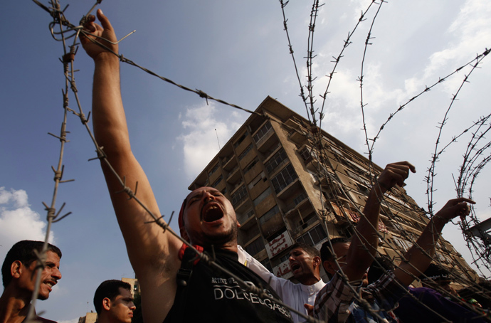 Members of the Muslim Brotherhood and supporters of deposed Egyptian President Mohamed Mursi shout slogans behind barbed wire outside the Republican Guard headquarters in Cairo July 19, 2013 (Reuters / Amr Abdallah Dalsh)