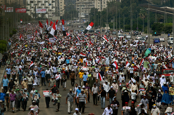 Supporters of the Muslim Brotherhood and ousted Egyptian president Mohamed Morsi raise pictures of the toppled leader and wave the national flag during a demonstration in Cairo, on July 19, 2013 (AFP Photo / Marwan Naamani)