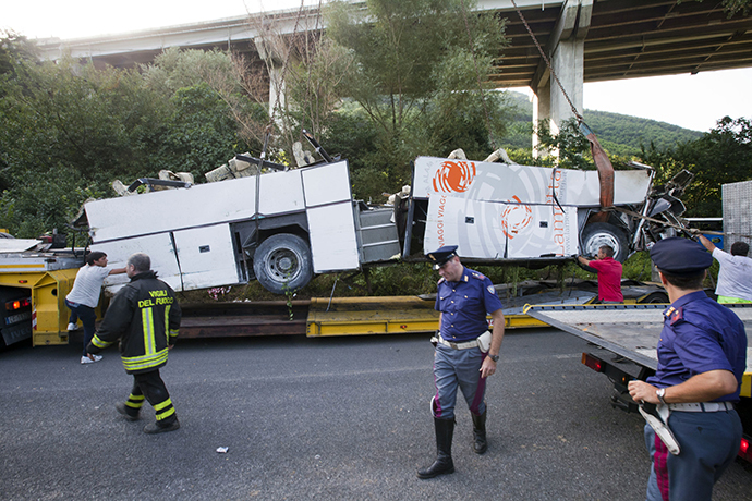 Workers remove the wreck of a bus on July 29, 2013 near Baiano, following a crash the day before on the road between Monteforte Irpino and Baiano, southern Italy. (AFP Photo / Carlo Hermann)