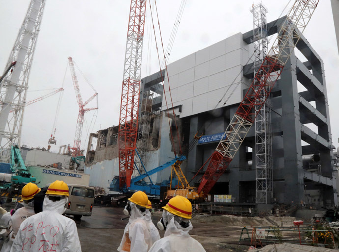 Reporters and Tokyo Electric Power Co workers look up the unit 4 reactor building during a media tour at TEPCO's Fukushima Dai-ichi nuclear plant in the town of Okuma, Fukushima prefecture in Japan on June 12, 2013. (AFP Photo)