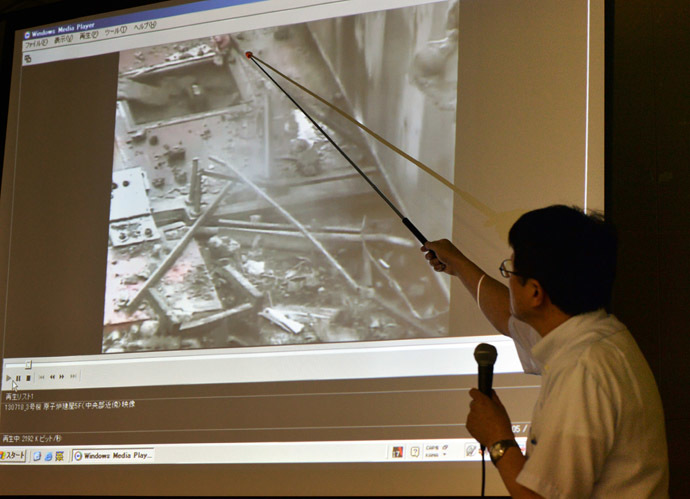 Masayuki Ono, acting head of Tokyo Electric Power Co (TEPCO) nuclear power and facilities section, displays an image showing steam rising from the unit 3 reactor building of TEPCO's Fukushima Dai-ichi nuclear plant at a news conference at the company's headquarters in Tokyo on July 18, 2013. (AFP Photo/Yoshikazu Tsuno)