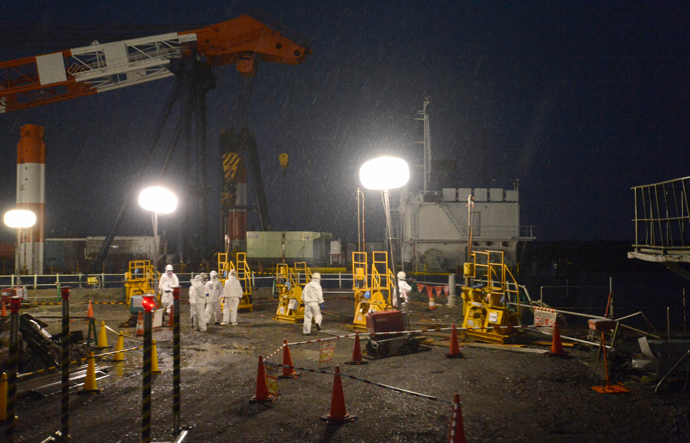 Workers wearing protective suits and masks operate a soil improvement work site of the shore barrier to stop radioactive water from leaking into the sea, near the No.1 and No.2 reactor buildings of the tsunami-crippled Fukushima Daiichi nuclear power plant (Reuters / Kyodo)