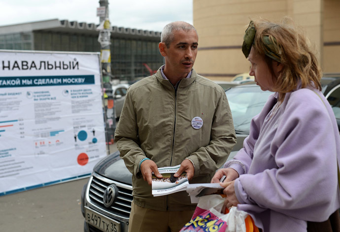 A member of Alexei Navalny's election campaign team provides information on Navalny's electoral program to a woman on a street near the Kursky Train Station. (RIA Novosti/Vladimir Pesnya)