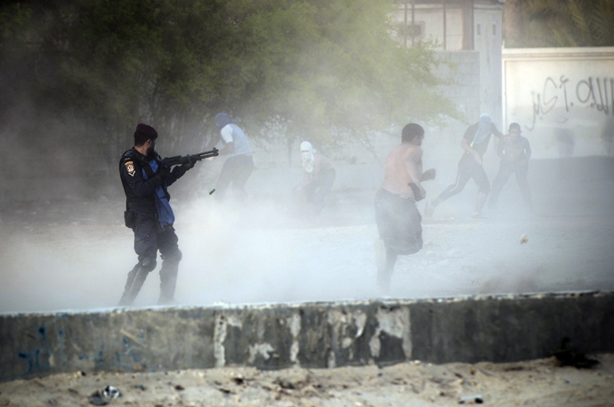 A Bahraini riot policeman ( L ) fires bird shot toward anti-government protestors during demonstration against the ruling regime in the village of Shakhora, west of Manama, on August 14, 2013 (AFP Photo / Mohammed Al-Shaikh)