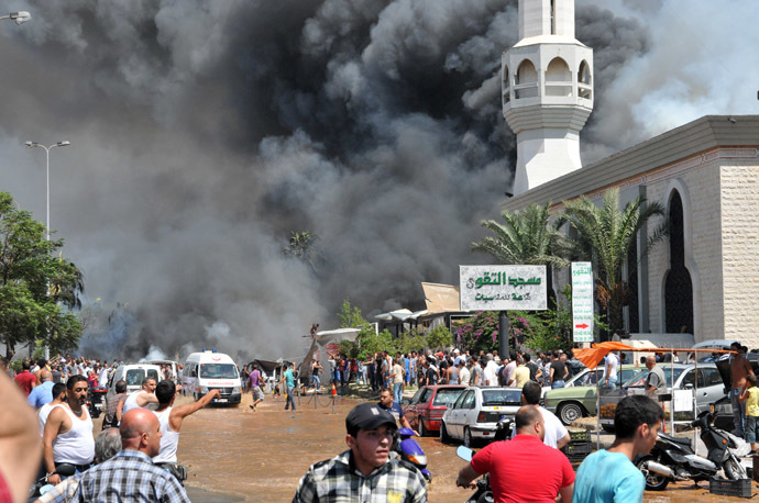 Smoke is seen above people gathering outside a mosque on the site of a powerful explosion in the northern Lebanese city of Tripoli on August 23, 2013. (AFP Photo/Ibrahim Chalhoub)