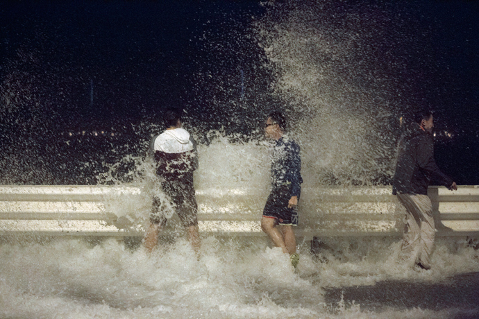 People react as waves splash on to the road during Typhoon Usagi in Hong Kong September 22, 2013 (Reuters / Tyrone Siu)