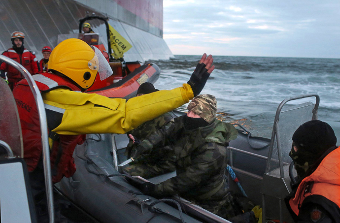 Camouflage clad mask wearing officer of Russian Coast Guard (C) pointing a knife at a Greenpeace International activist (L) during an environmentalists' attempt to climb Gazpromâs âPrirazlomnayaâ Arctic oil platform somewhere off Russia north-eastern coast in the Pechora Sea on September 18, 2013 (AFP Photo / Greenpeace / Denis Sinyakov)