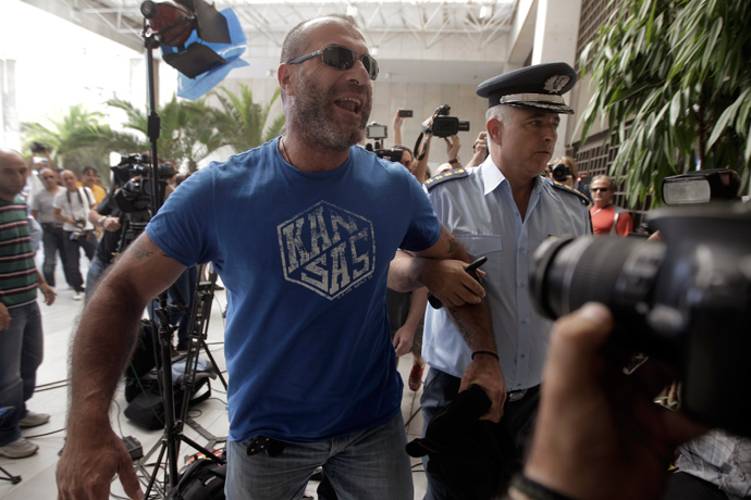 Lawmaker of extreme-right Golden Dawn party Nikolaos Mihos (L) is escorted by a police officer as he arrives at the Greek police headquarters in Athens September 28, 2013 (Reuters / John Kolesidis)