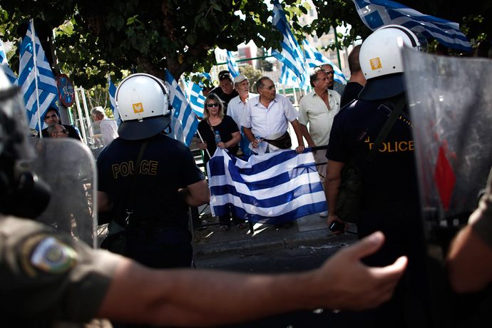 Supporters of the extreme far-right Golden Dawn party hold Greek flags as riot police tries to move them away during a protest in solidarity of the arrested lawmakers in front of the police headquarters in Athens on September 28, 2013 (AFP Photo / Angelos Tzortzinis)