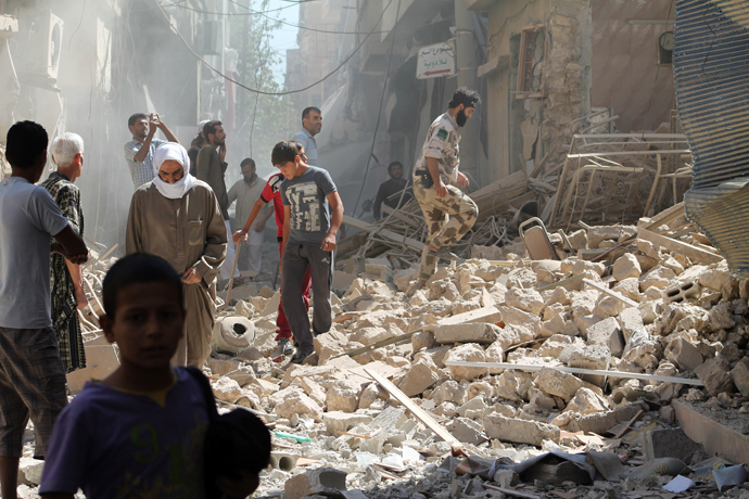 Residents of Syria's eastern town of Deir Ezzor walk past the debris of a building reportedly hit by a missile (AFP Photo / Ahmad Aboud)