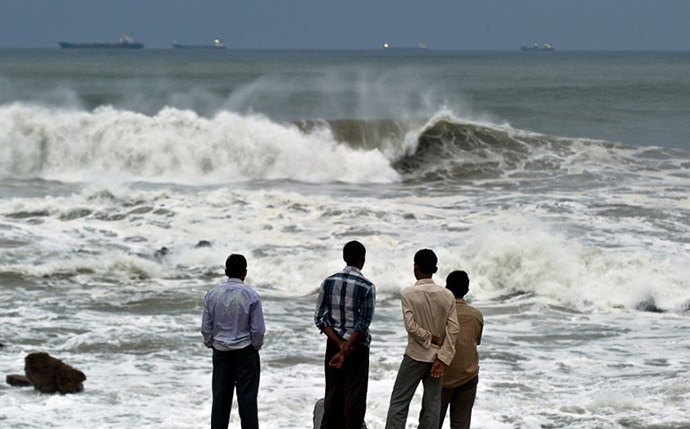 Indian youth stand on the shore as high tidal waves hit the coastline in Visakhapatnam on October 12, 2013. (AFP Photo / Manan Vatsyayana)