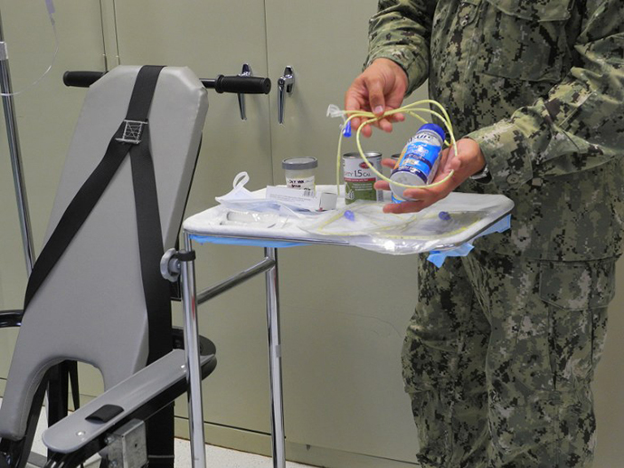 A US naval medic holds liquid food supplement force fed to hunger strikers at the US Naval Base in Guantanamo Bay, Cuba on August 7, 2013. (AFP Photo / Chantal Valery)