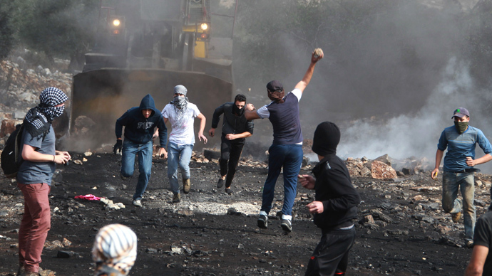 Palestinian protesters throw stones at an Israeli army's tractor during clashes following a protest against the expropriation of Palestinian land by Israel in the village of Kfar Qaddum, in the northern West Bank, on November 1, 2013. (AFP Photo / Jaafar Ashtiyeh)