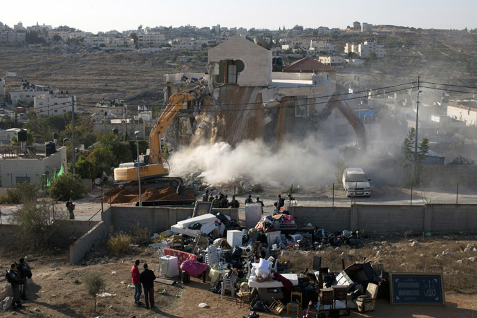 An Israeli municipality worker uses a mechanical shovel to demolish a house, belonging to a Palestinian family, that was built without municipal permission in the Arab east Jerusalem neighborhood of Beit Hanina on October 29, 2013. (AFP Photo)