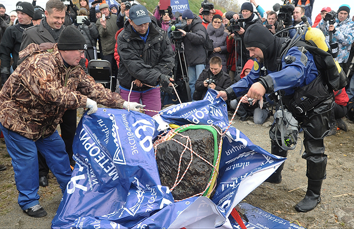 Divers with a meteor fragment retrieved from Lake Chebarkul on October 16, 2013. (Aleksandr Kondratuk / RIA Novosti)