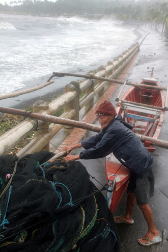 A fisherman secures his wooden fishing boat along the sea wall amidst strong winds as Typhoon Haiyan hit the city of Legaspi, Albay province, south of Manila on November 8, 2013 (AFP Photo / Charism Sayat)