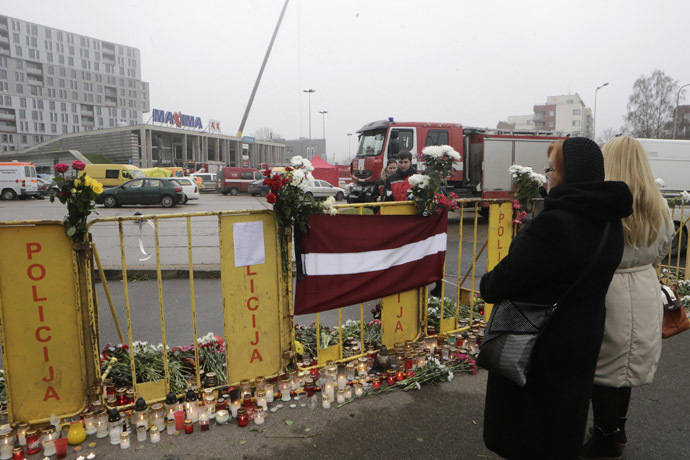 People gather near lit candles around a collapsed supermarket in Riga November 23, 2013. (Reuters/Ints Kalnins)