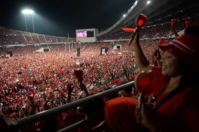 Thai pro-government Red Shirt supporters wave clappers and cheer leaders' speeches during a rally at a stadium in Bangkok on November 30, 2013. (AFP Photo/Christophe Archambault)