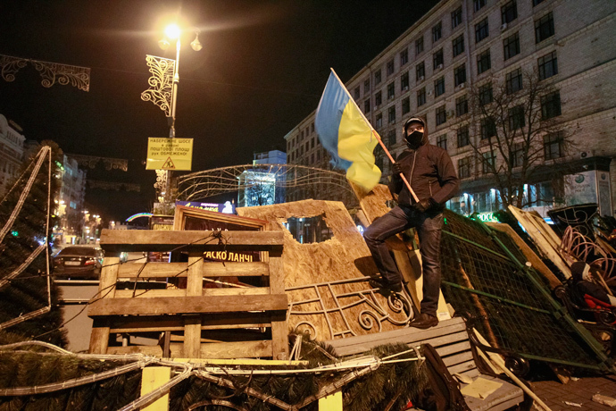 A protester carries a Ukrainian flag as he stands on barricades at Independence Square in Kiev December 2, 2013. (Reuters / Gleb Garanich)