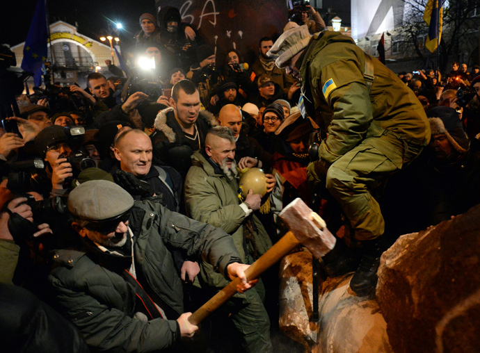 A protester breaks apart a statue of Lenin at a monument in his honor after it was pulled down during a mass rally called "The March of a Million" in Kiev's Independence Square on December 8, 2013. (AFP Photo / Vasily Maximov)