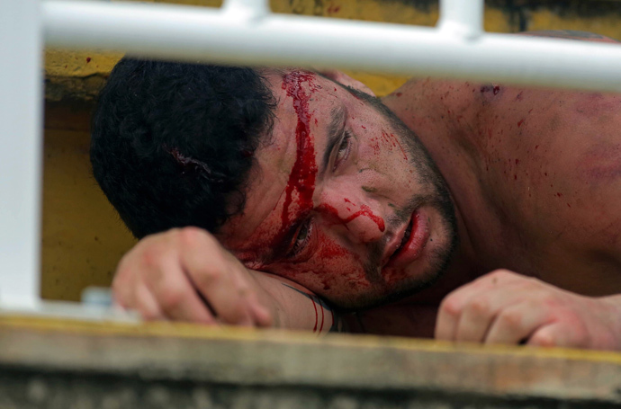 A fan of Parana's Atletico PR lies injured after being hit by fans of Rio de Janeiro's Vasco da Gama, during a Brazilian Championship football match in Joinville, Santa Catarina, on December 8, 2013. (AFP Photo / Heuler Andrey)