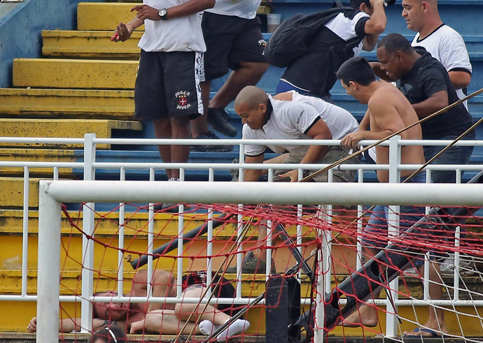 Fans of Rio de Janeiro's Vasco da Gama attack a fan of Parana's Atletico PR, during a Brazilian Championship football match in Joinville, Santa Catarina, on December 8, 2013. (AFP Photo / Heuler Andrey)