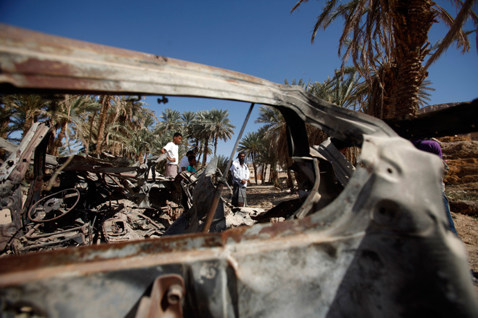 People gather near the wreckage of a car destroyed by a U.S. drone air strike that targeted suspected al Qaeda militants in August 2012, in the al-Qatn district of the southeastern Yemeni province of Hadhramout February 5, 2013 (Reuters / Khaled Abdullah)