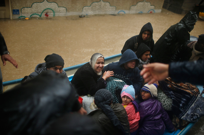 Members of a Palestinian family travel on a boat after being evacuated from their house which was flooded with rainwater on a stormy day in the northern Gaza Strip December 14, 2013. (Reuters / Mohammed Salem)